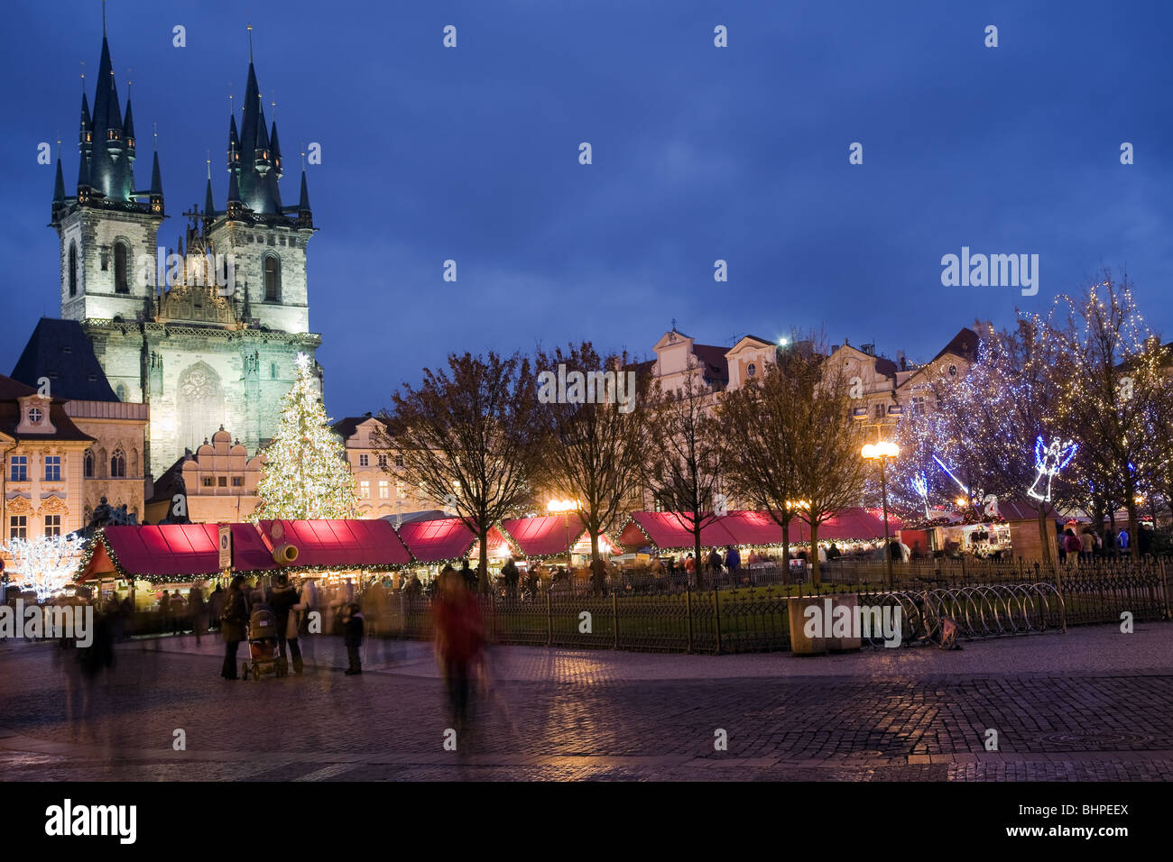 Sunset on Old Town Square with St. Teyn Gothic cathedral in Prague during Christmas market with walking people. Stock Photo