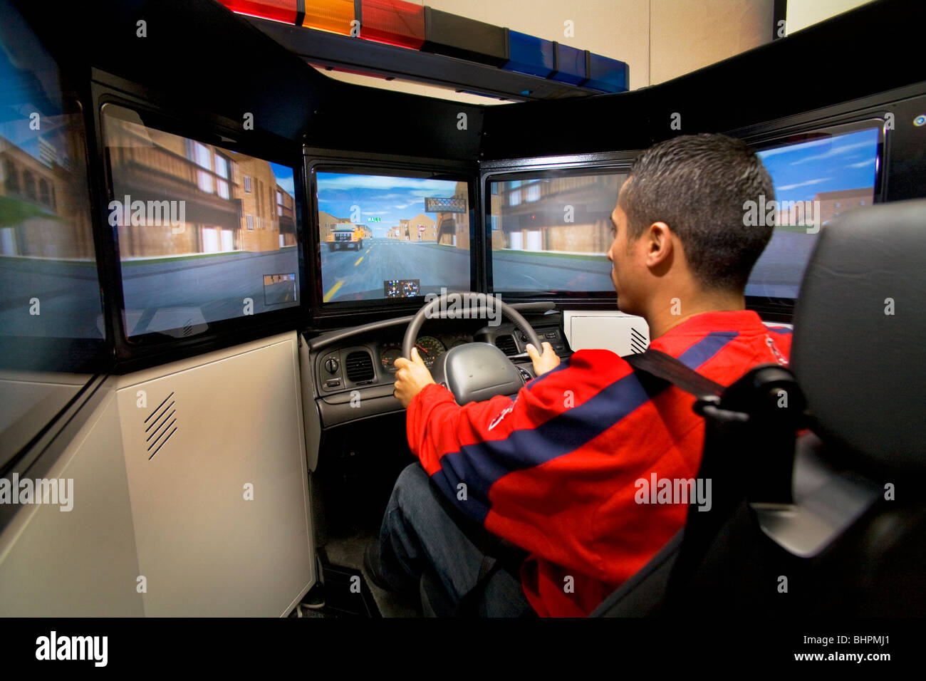 A police officer practices high speed driving skills in a patrol car simulator with a real steering wheel and seat. Stock Photo