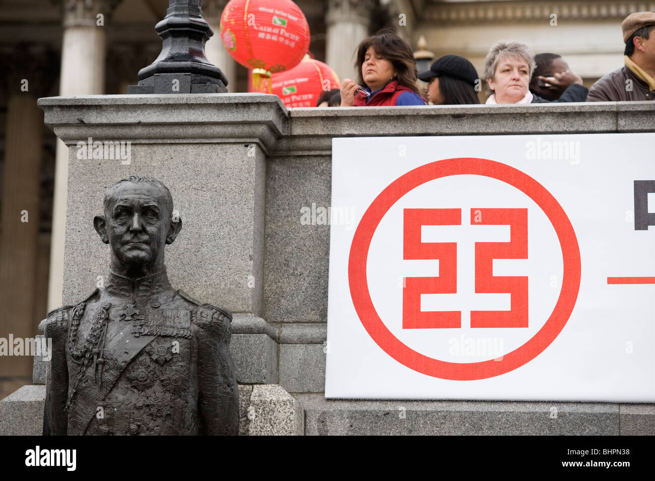 Statue, people and Chinese symbol on a banner at the Chinese New Year celebrations in Trafalgar Square London UK Stock Photo