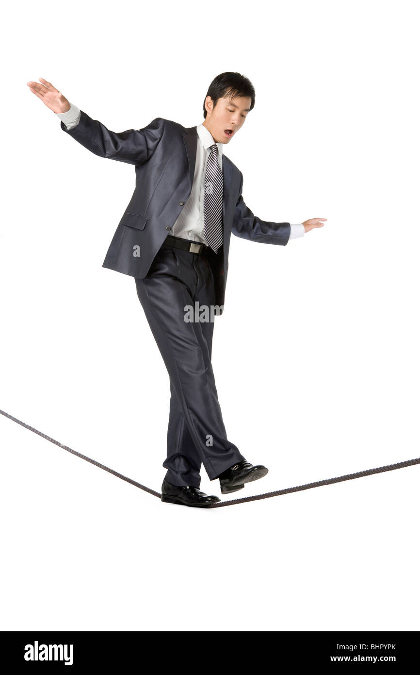 Businessman walking on rope in mid-air Stock Photo