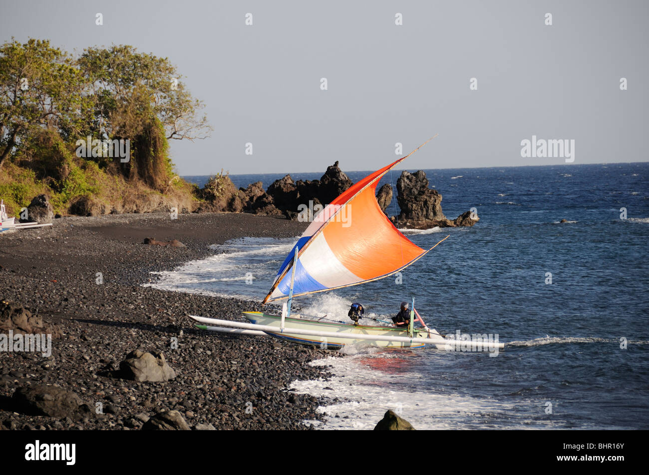 Outrigger-Canoe sailing at vulcanic beach, Bali, Indonesia, Indo-Pacific Ocean Stock Photo