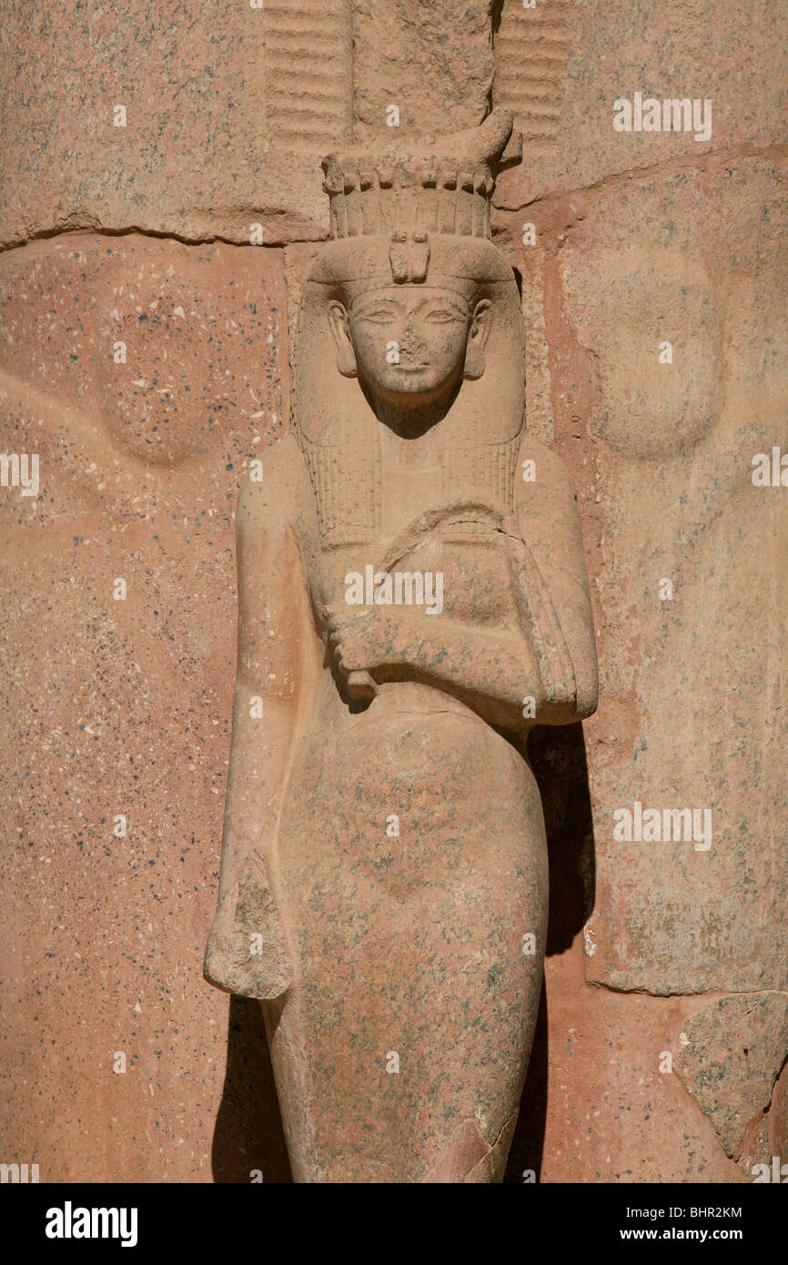 Statue of queen Bent'anta standing between Ramesses II's feet at the First Courtyard of Karnak Temple in Luxor, Egypt Stock Photo