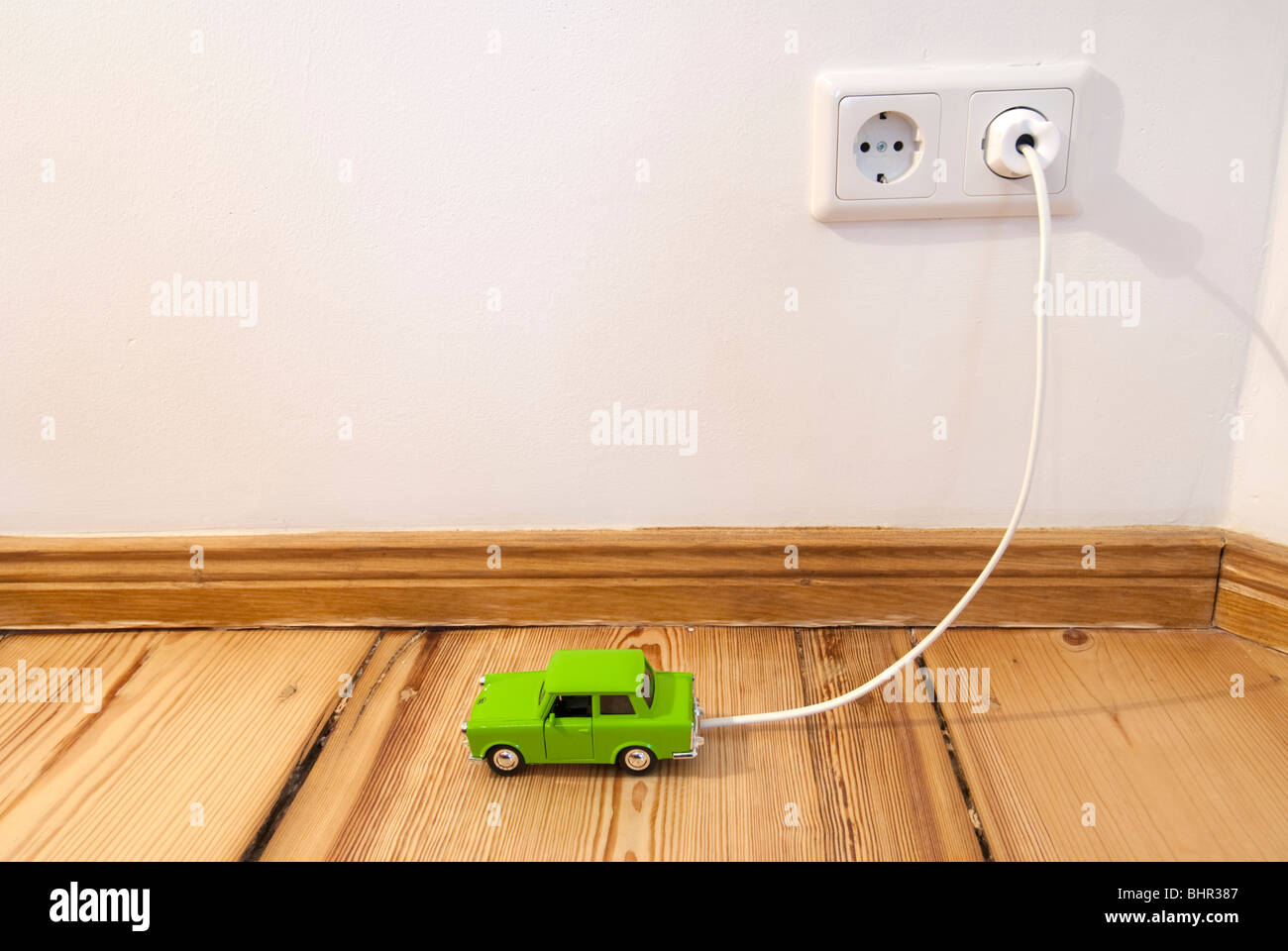 Concept of toy electric car being recharged by plug-in connection to electric supply in the home Stock Photo