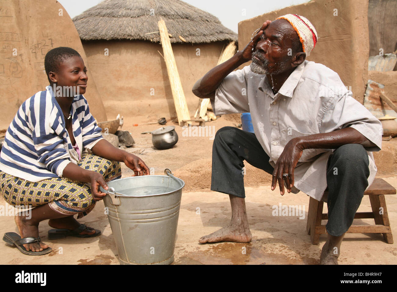 A daughter helps her elderly blind father to wash in a village in