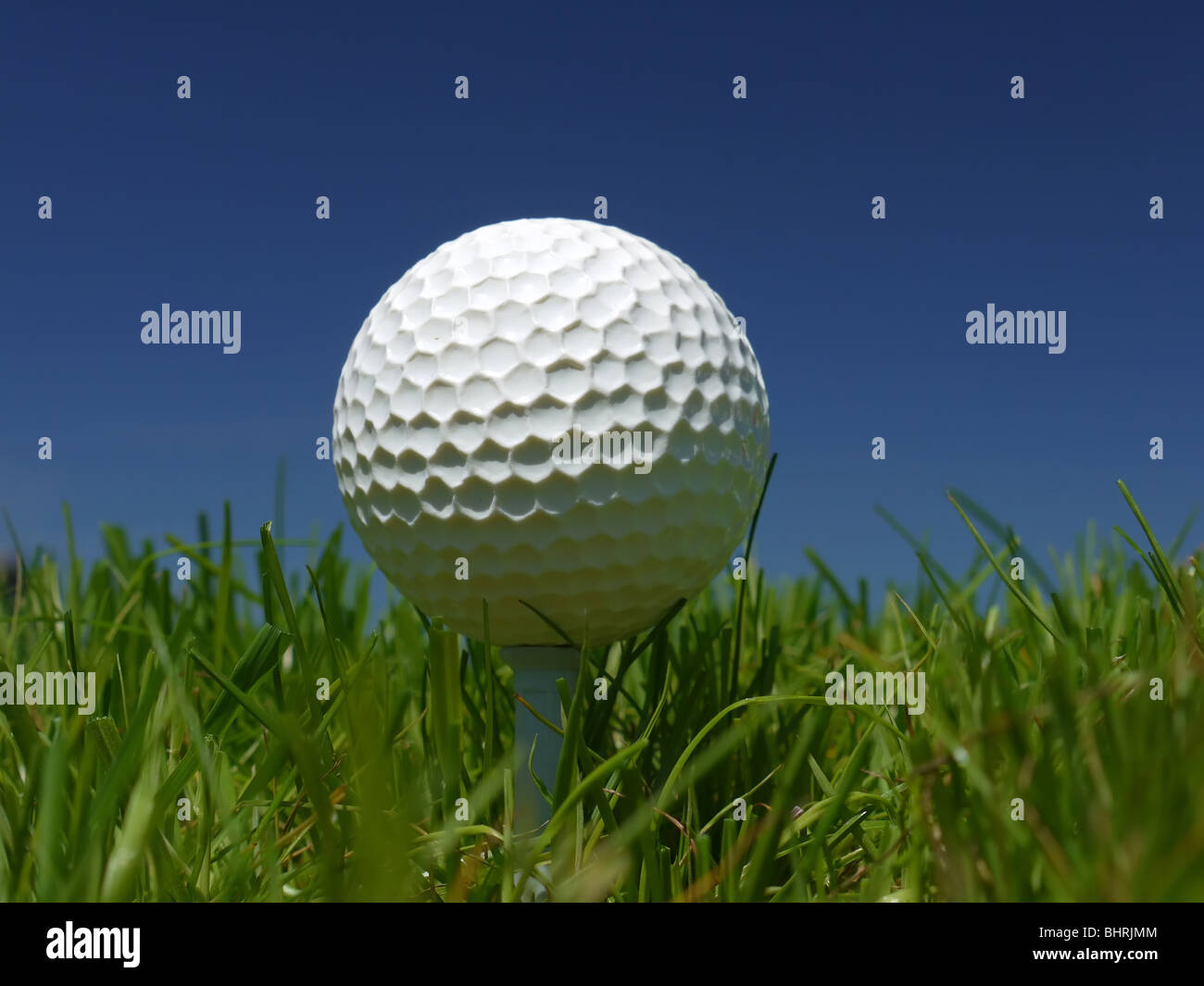 Golf ball on tee in the grass over blue sky Stock Photo