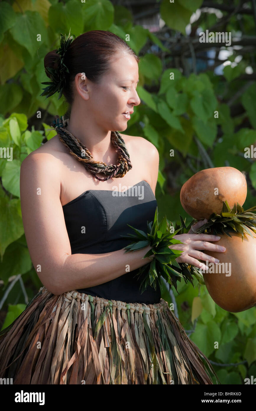 Hula dancer in traditional ti leaf skirt holds ipu heke before kahiko hula performance. Stock Photo