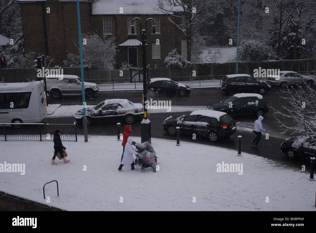 The school run in Heston village centre on a snowy day in winter, West