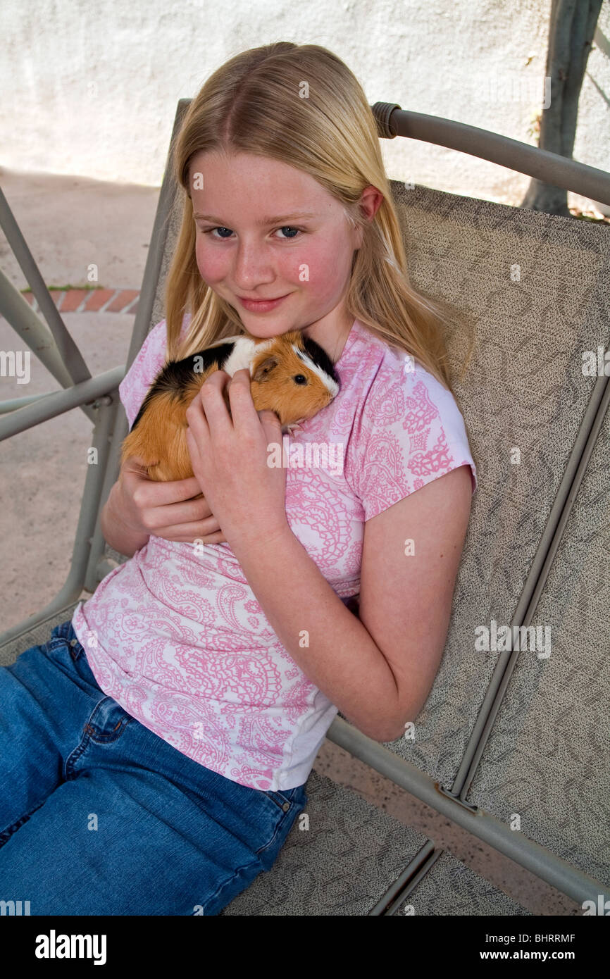 Portrait 10-11 year old girl relaxes relaxing playing with cute Guinea pig outside swing United States Tween tweens young person people  MR  ©  Myrleen Pearson Stock Photo