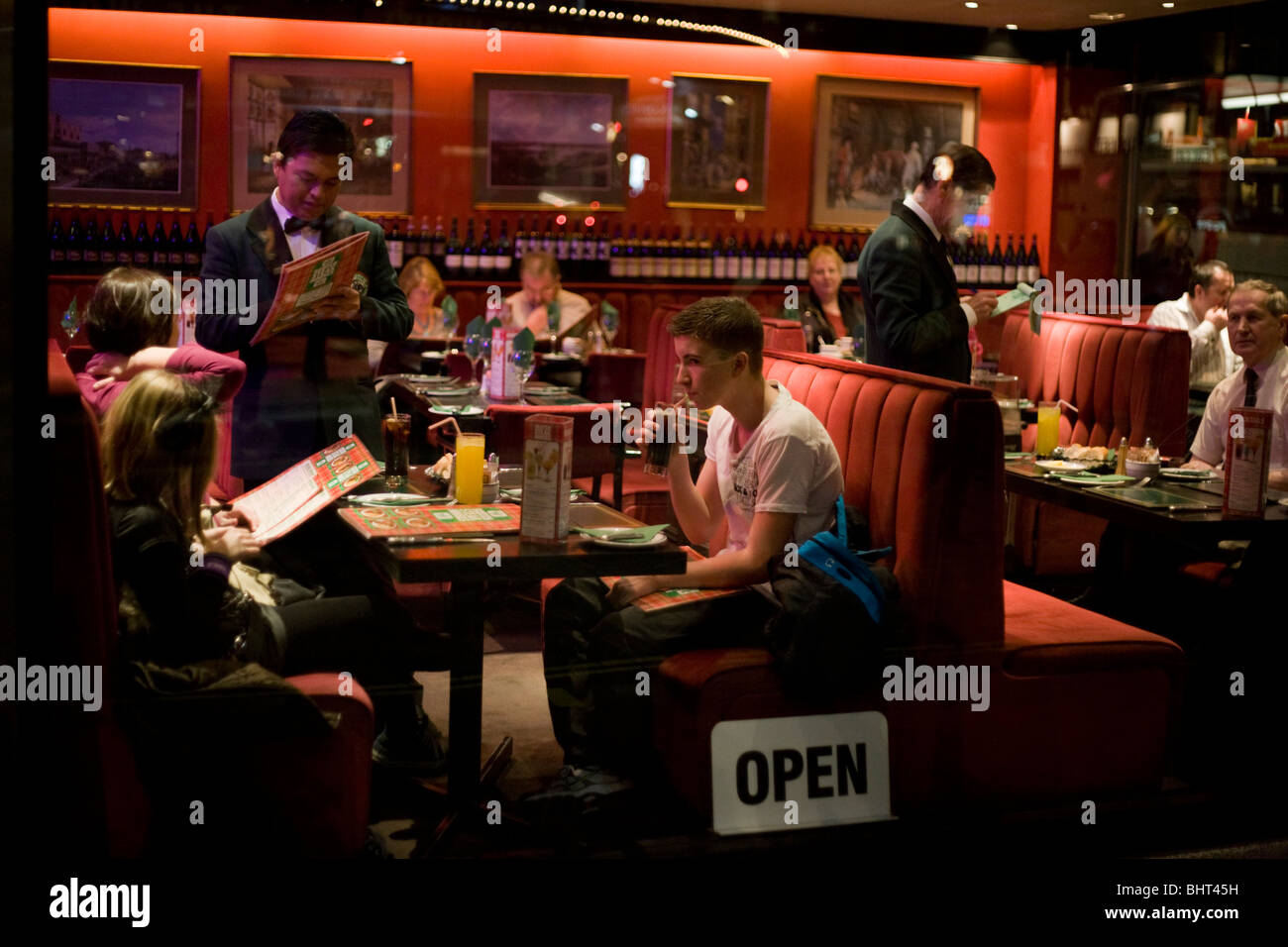 Seen through the window of an Angus Steakhouse restaurant, a family order their dinners from a waiter. Stock Photo