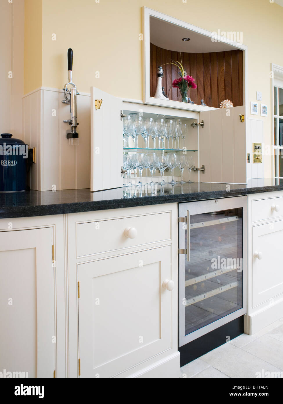 Wine glasses on shelves in kitchen cupboard above refrigerated wine