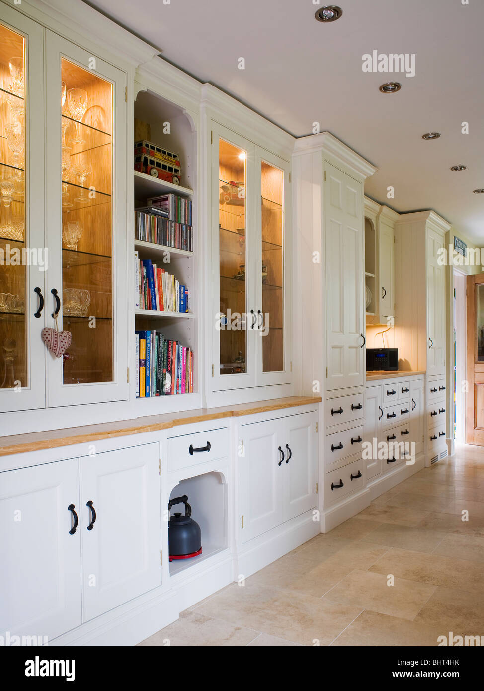 Lighting in white fitted cupboards with glazed doors in traditional