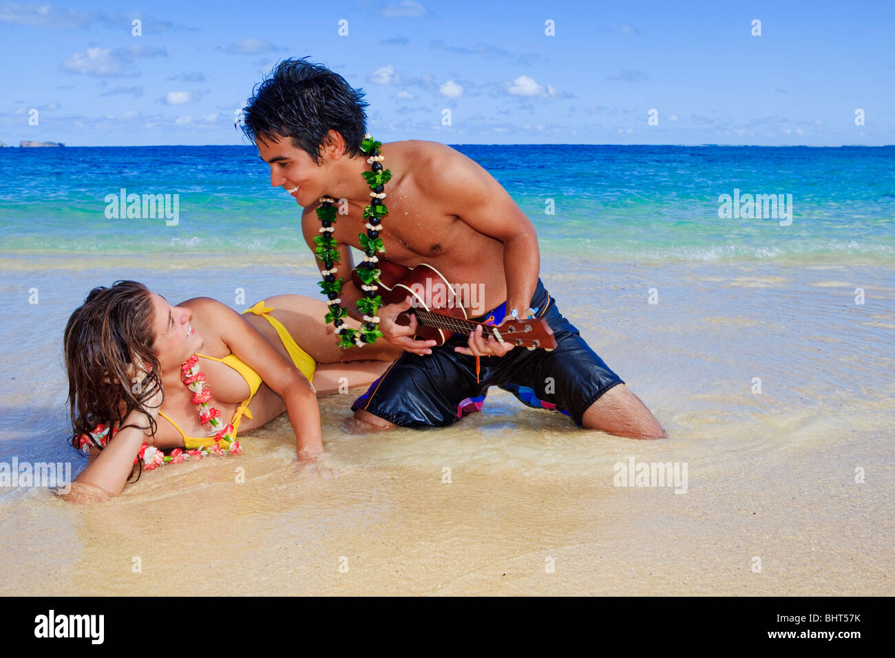 pacific island man plays his ukulele for a young woman on a hawaii