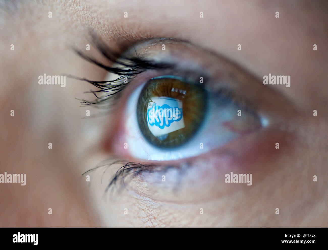 Skype internet telephone and video website logo reflected in womans eye from computer screen Stock Photo