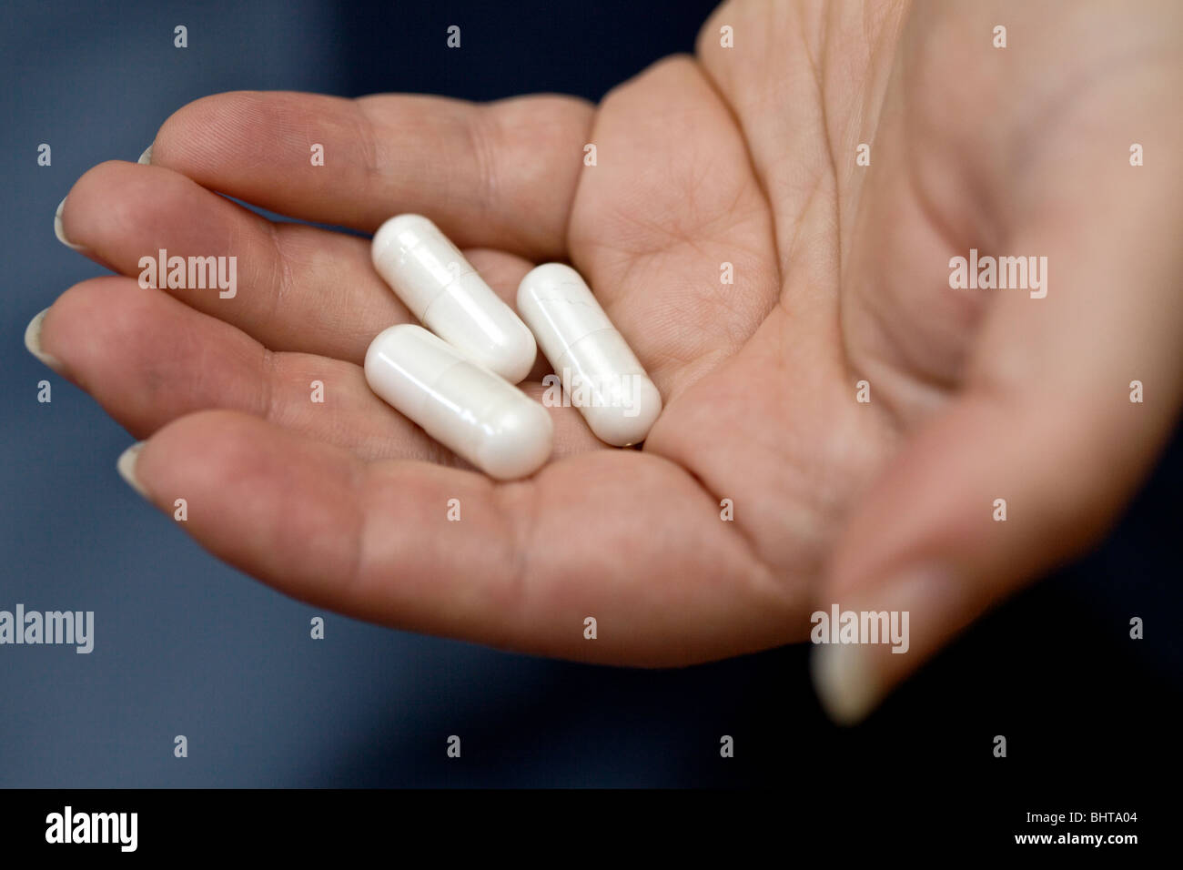 Capsules containing white powder in woman's hand. Stock Photo