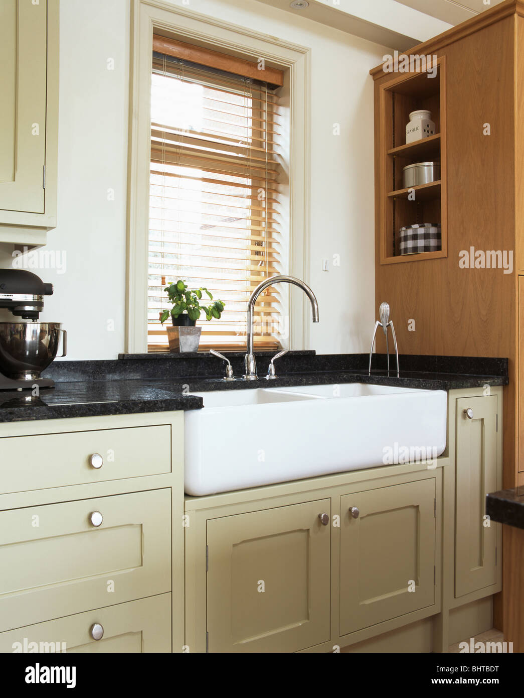 Double Belfast sink below window with slatted wooden blind in modern