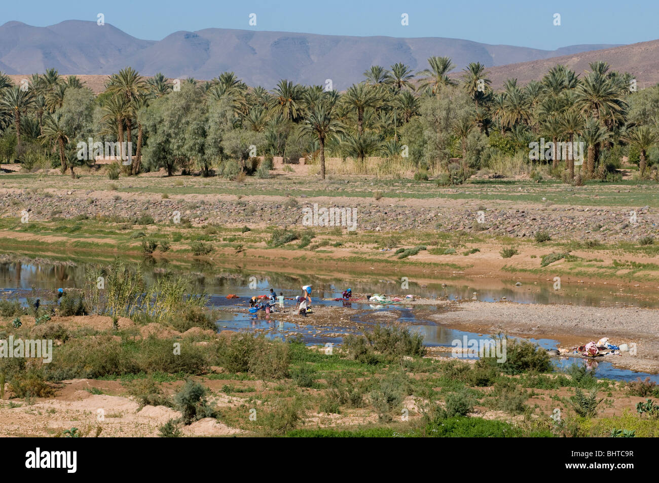 People washing clothes in a river near the fortress of Ait Benhaddou, Morocco Stock Photo