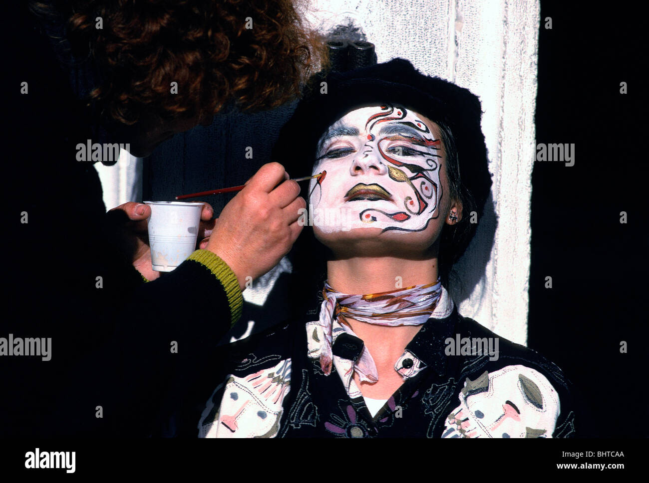 Person painting a man's face during carnival celebration, Venice, Italy Stock Photo