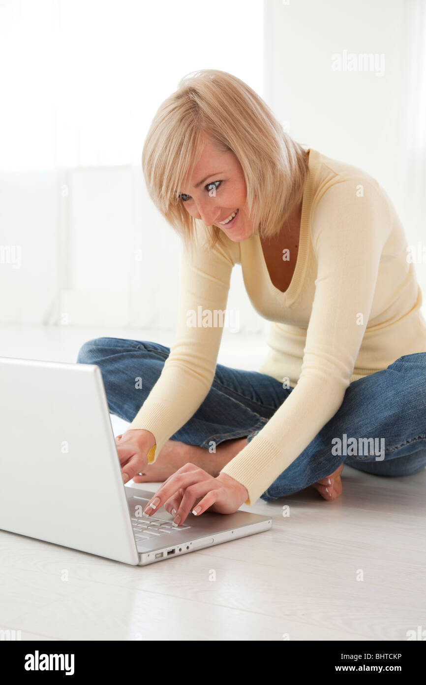 young woman sat crossed legged on the floor using laptop Stock Photo ...