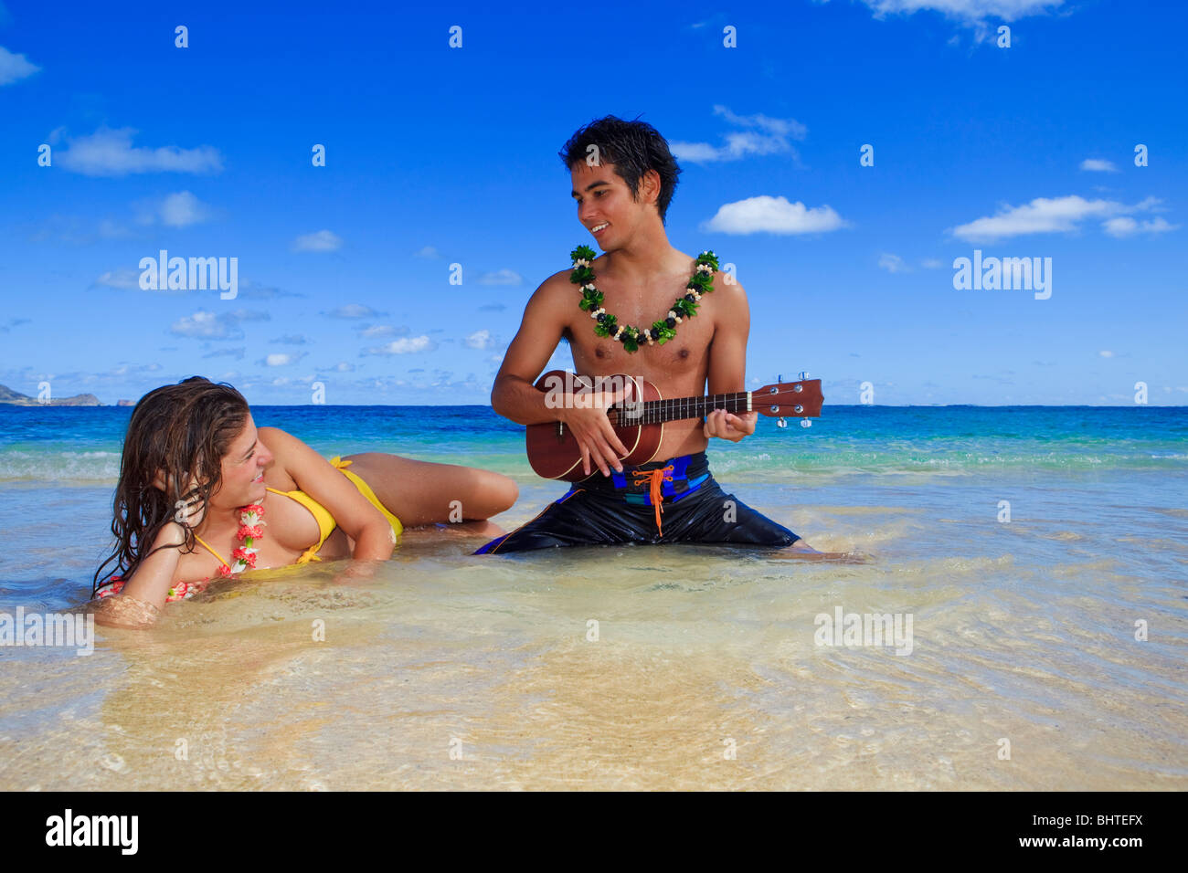 pacific island man plays his ukulele for a young woman on a hawaii