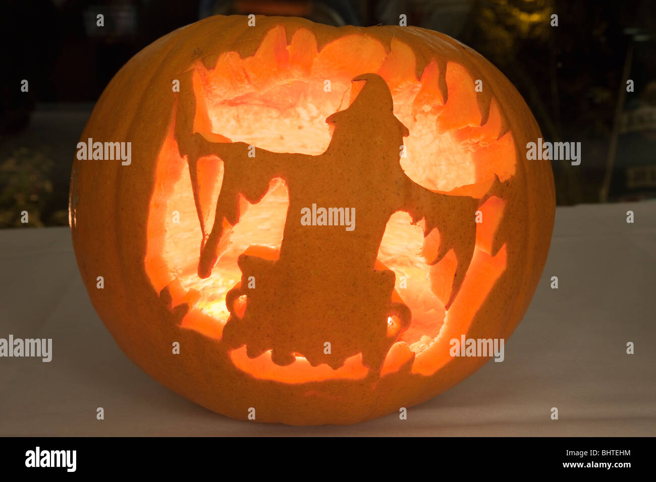 Scary Halloween pumpkin lantern with carved witch shape and illuminated with a candle glowing inside Stock Photo