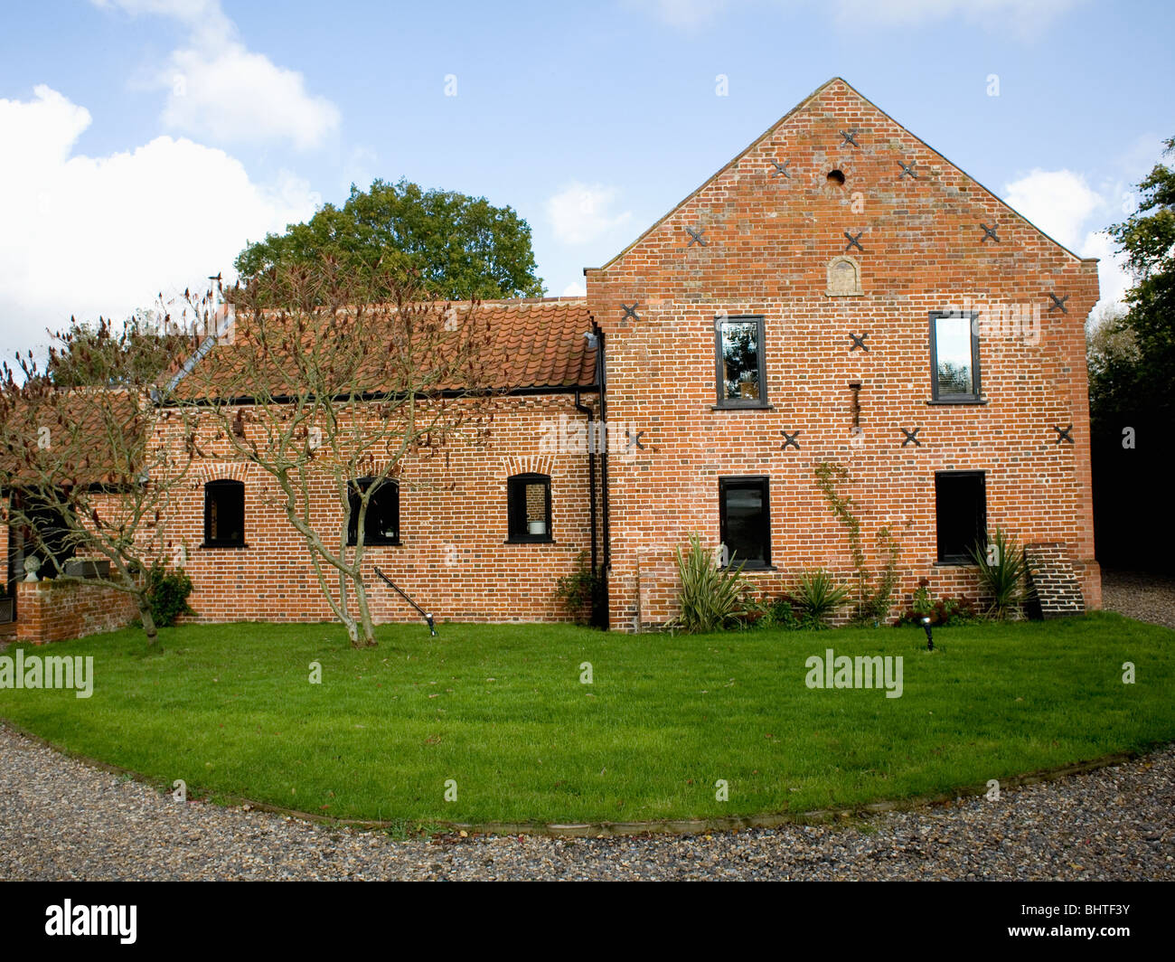 Lawn In Front Of Traditional Brick Built Country Barn Conversion