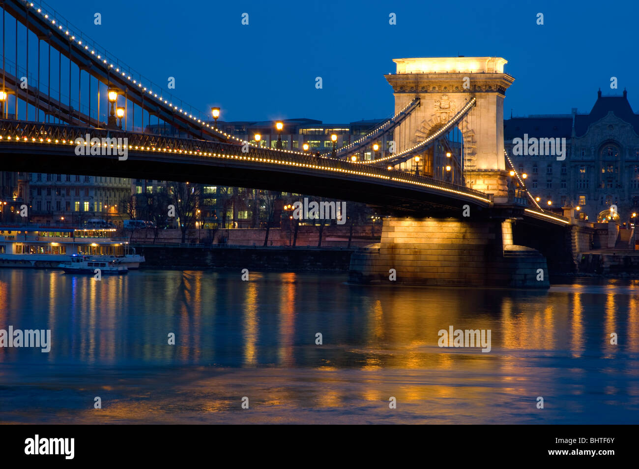 The Chain Bridge, Budapest, Hungary. Looking towards Pest, night time. Lighte reflected in the water of the Danube. Stock Photo