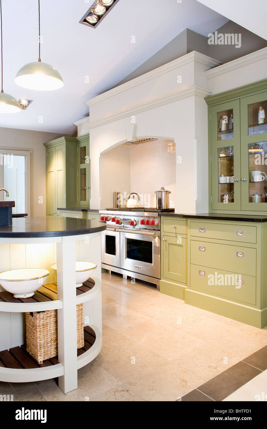 Limestone flooring in modern kitchen with pale green fitted units Stock