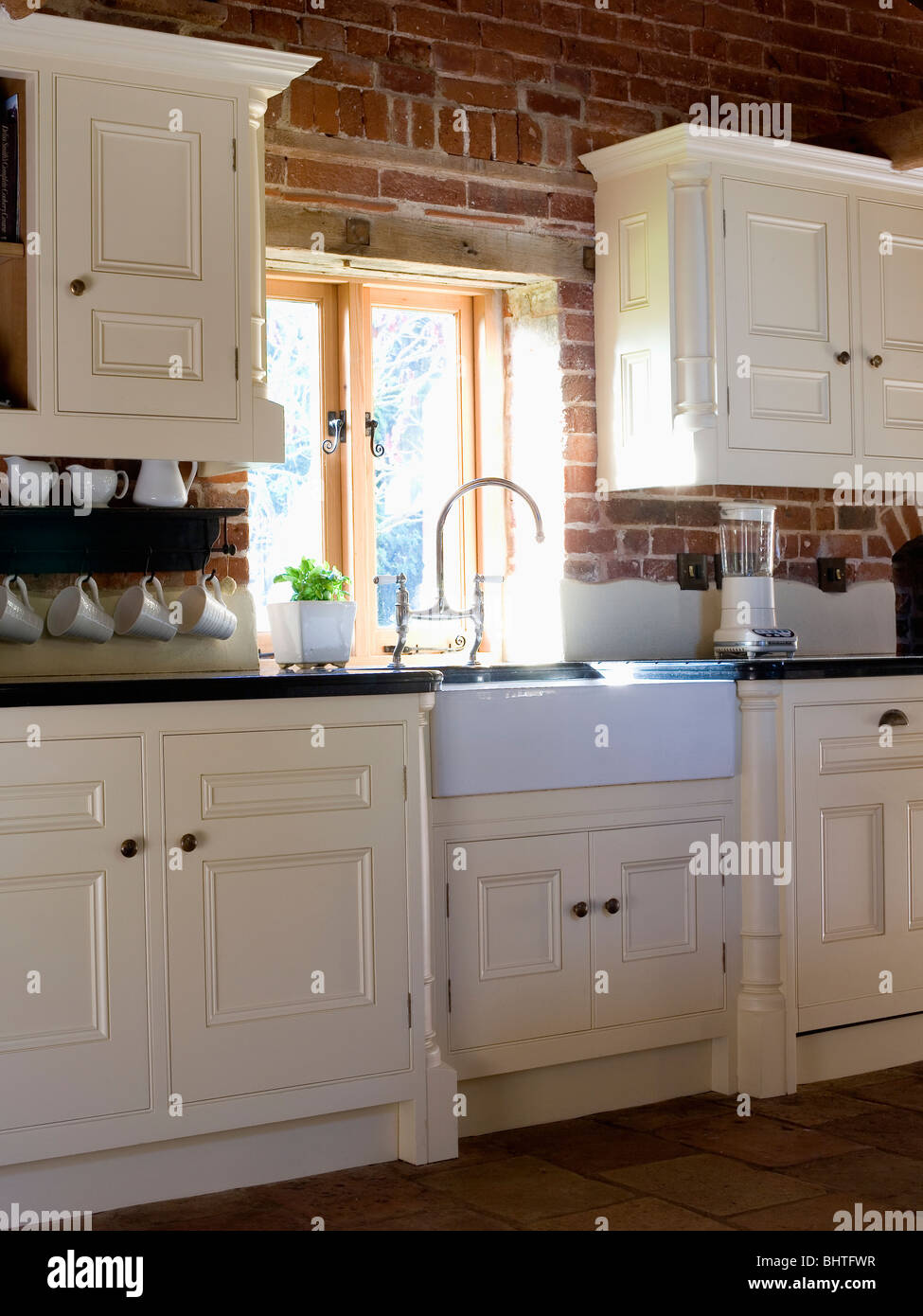 Belfast sink below window in country kitchen with fitted cream units