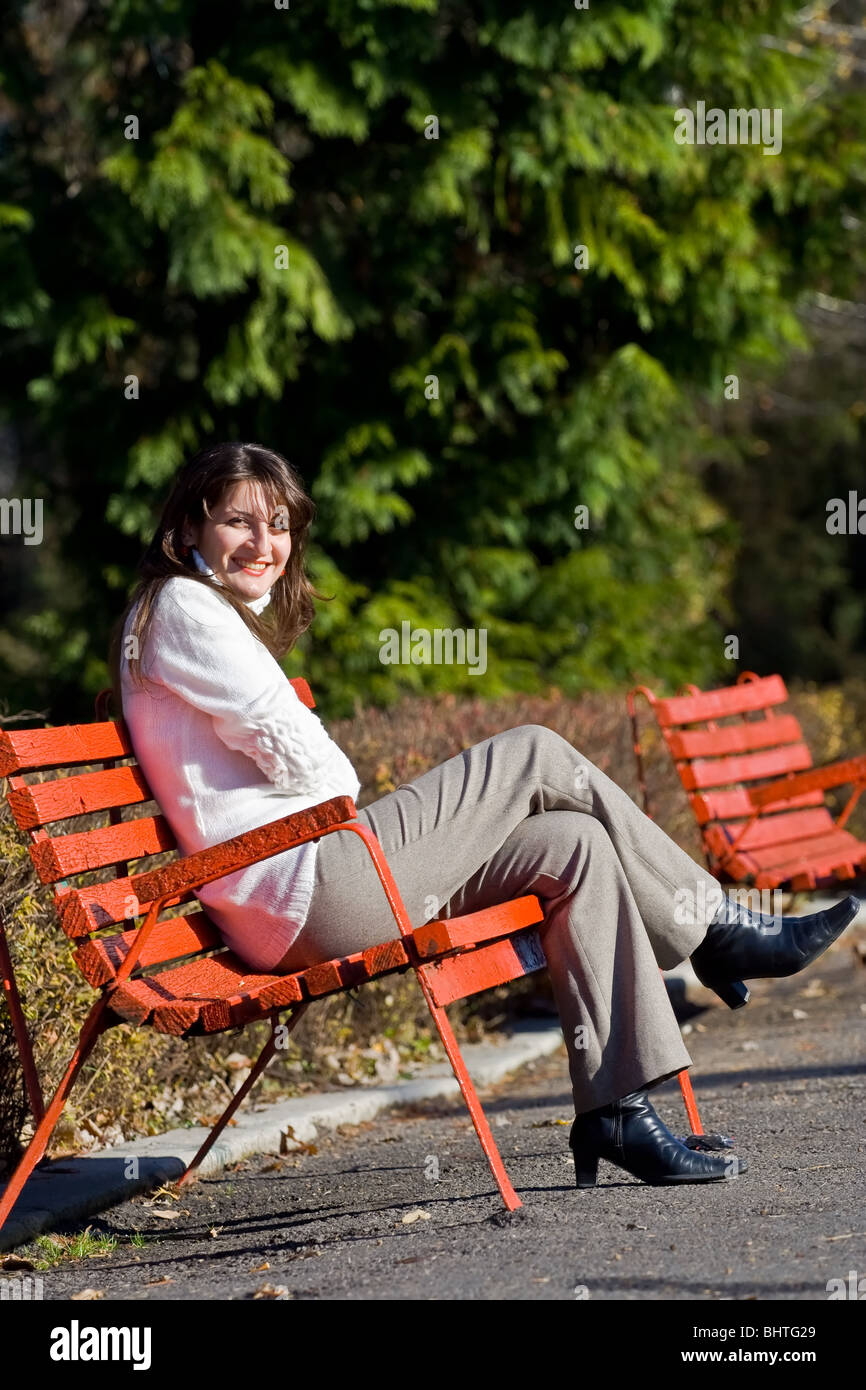 Happy young woman sitting on a bench in park Stock Photo - Alamy