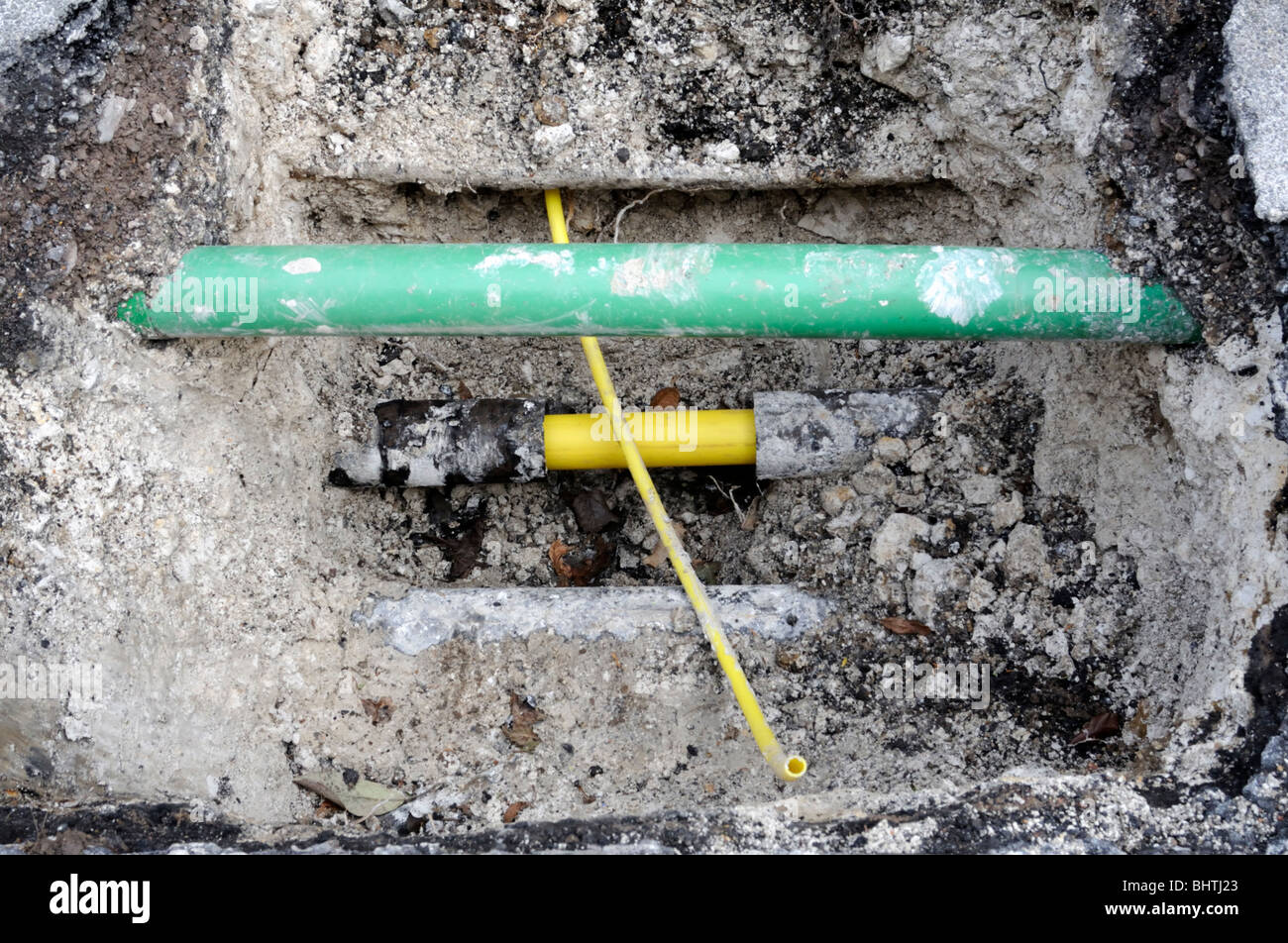 New yellow plastic domestic gas pipe ready to be connected to the new main pipe. The green pipe is for fiber optics. Stock Photo
