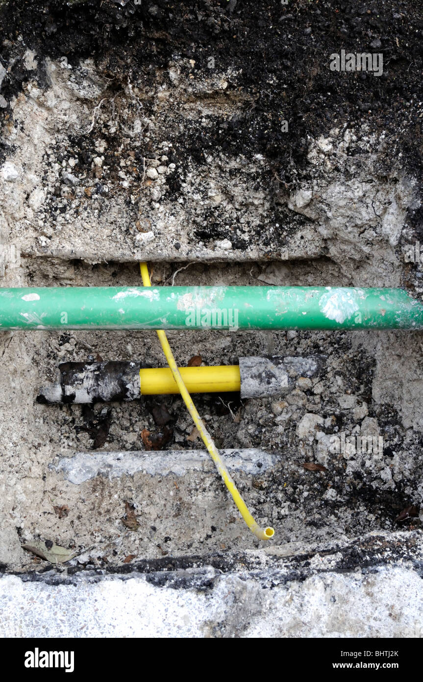 New yellow plastic domestic gas pipe ready to be connected to the new main pipe. The green pipe is for fiber optics. Stock Photo