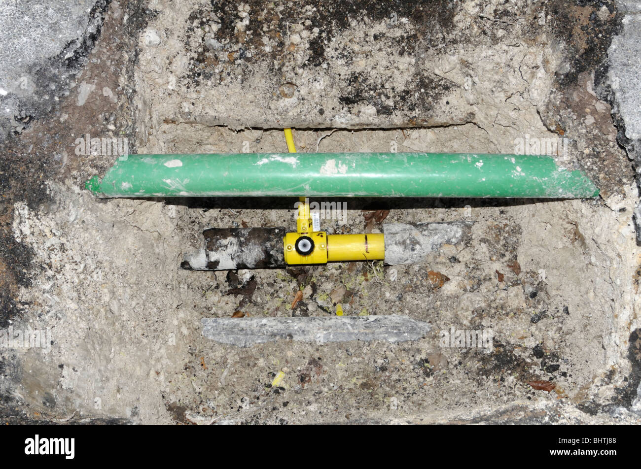 New yellow plastic domestic gas pipe connected to the new main pipe. The green pipe is for fiber optics. Stock Photo