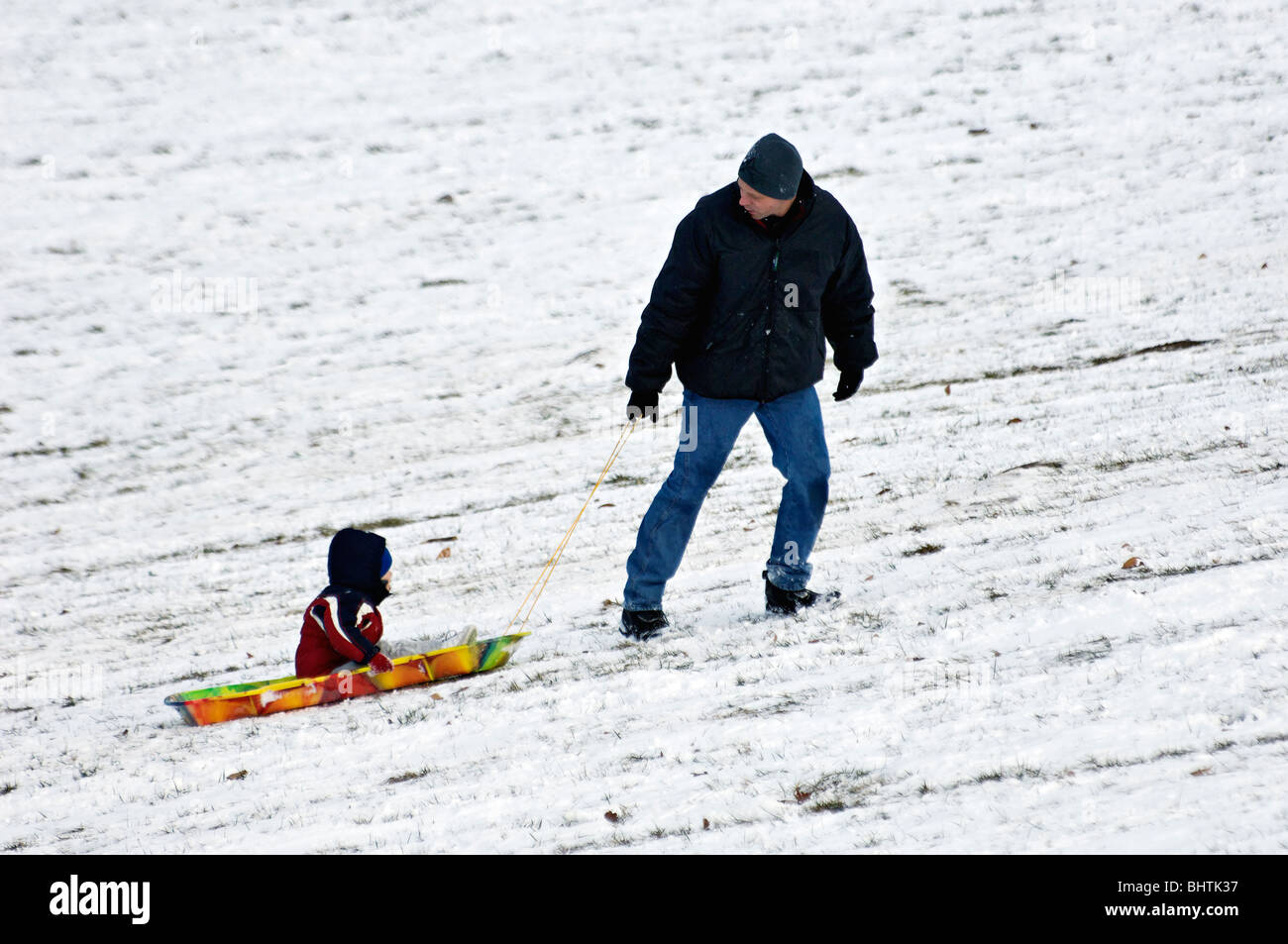 Father Pulling Young Son on Sled in Cherokee Park in Louisville, Kentucky Stock Photo