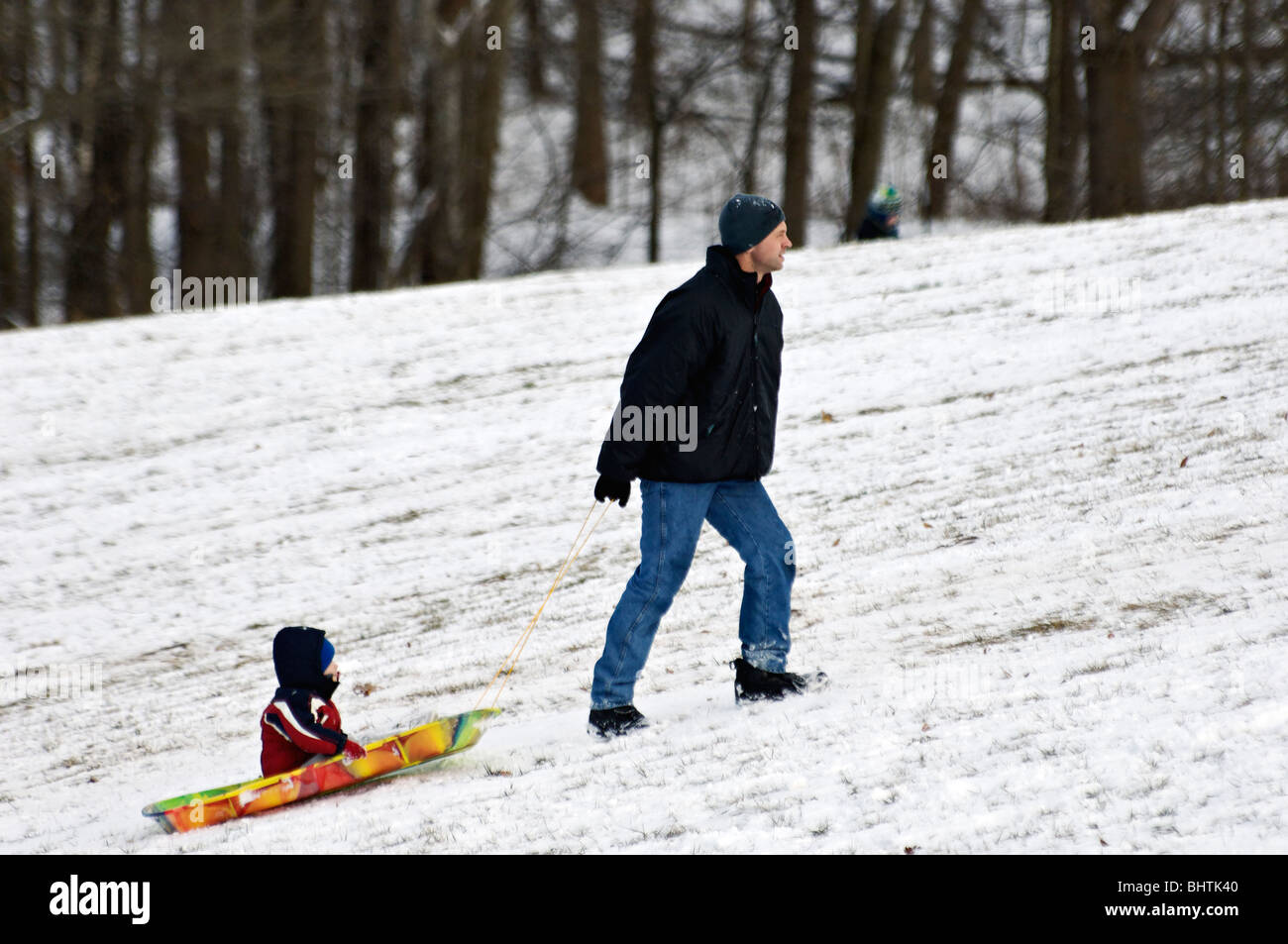 Father Pulling Young Son on Sled in Cherokee Park in Louisville, Kentucky Stock Photo