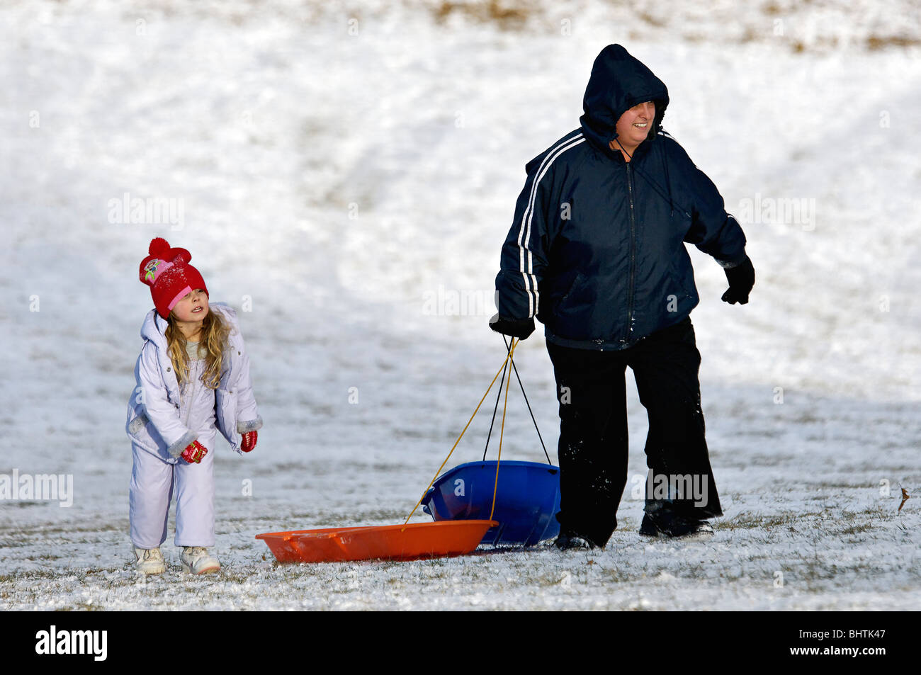 Mother with Young Daughter Pulling Sleds up Hill in Cherokee Park in Louisville, Kentucky Stock Photo