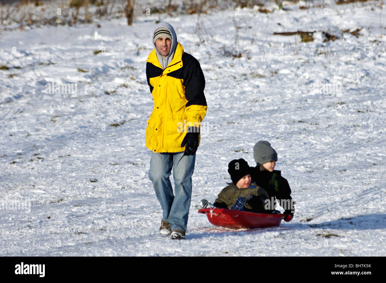 Father Pulling Two Young Boys on Sled in Cherokee Park in Louisville, Kentucky Stock Photo