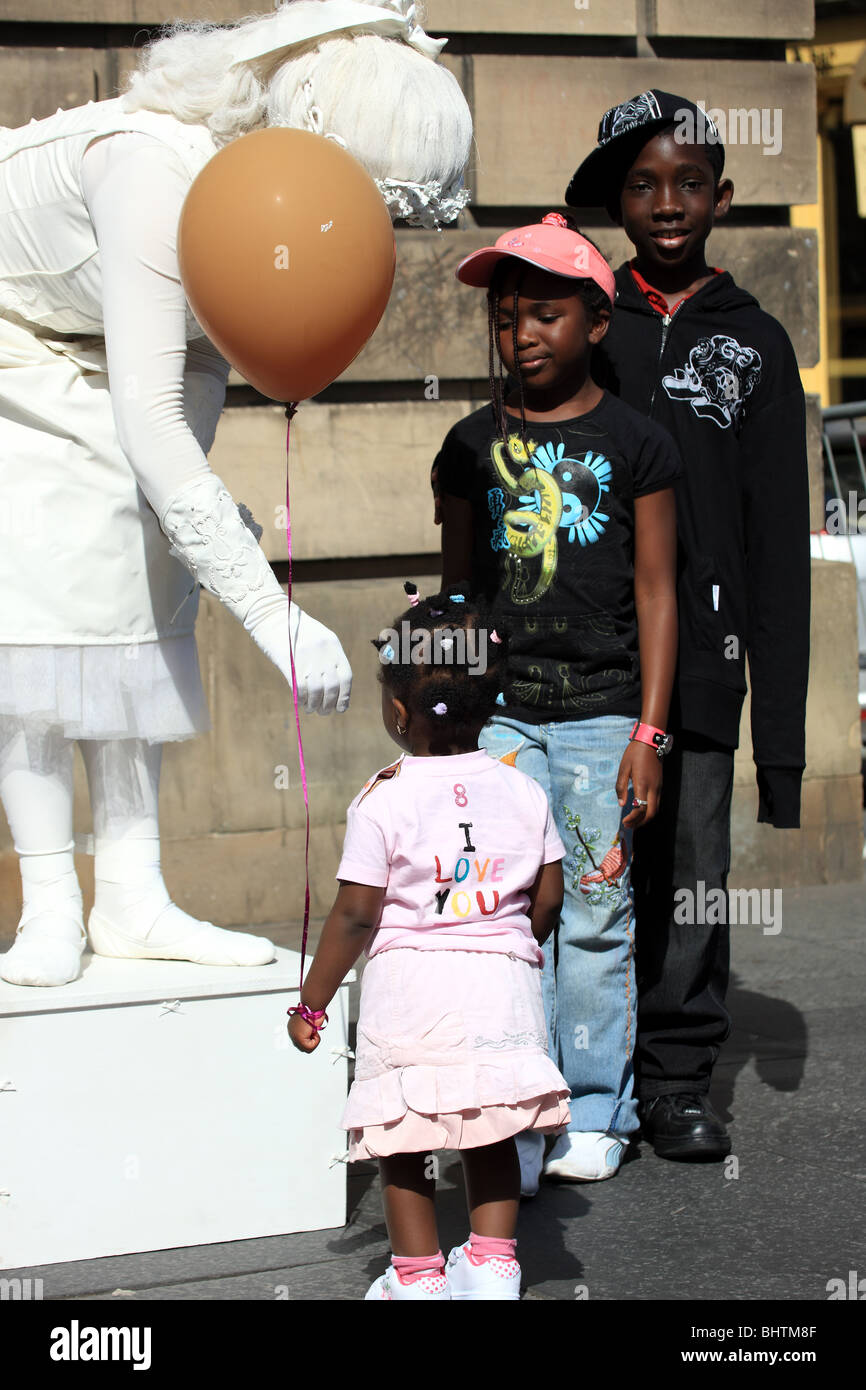 Three young children beside a street artist at the Edinburgh Festival Stock Photo