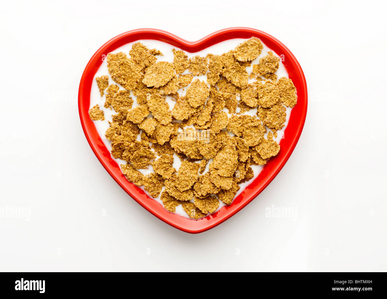 Studio shot of red heart shaped bowl from above with bran flakes and milk on a white background Stock Photo