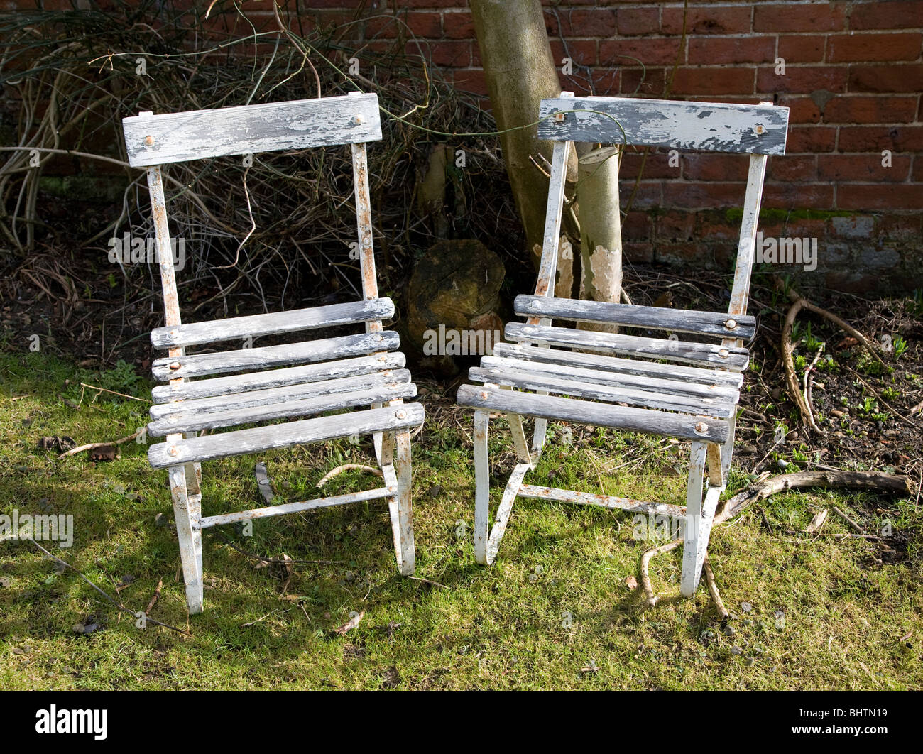 Two garden wooden chairs peeling white paint Stock Photo