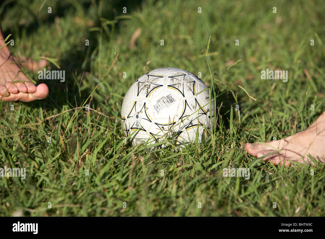 argentinian hispanic men playing football barefoot in the park on grass
