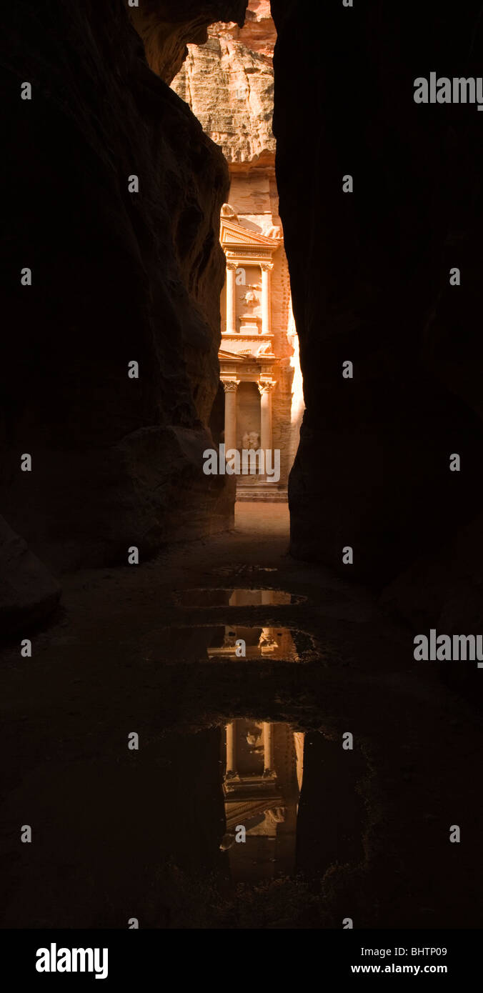 The Treasury or Al Khaznah reflecting in puddles at the ancient city of Petra seen trough the Siq canyon in Wadi Musa, Jordan. Stock Photo