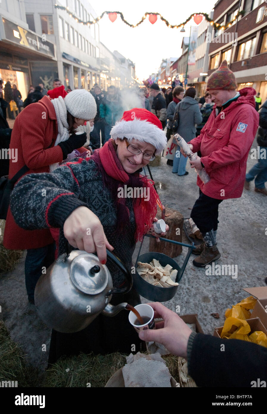 Woman serving coffee in the main street in the city Tromso, North Norway. Just before Christmas, advent. Stock Photo