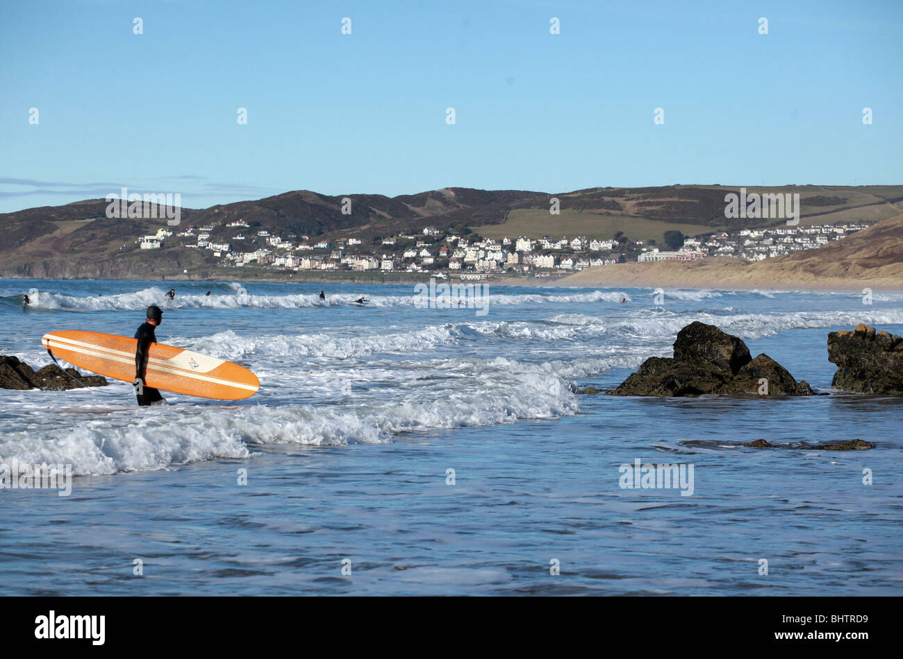 A surfer walks out of the surf at Woolacombe Devon Stock Photo