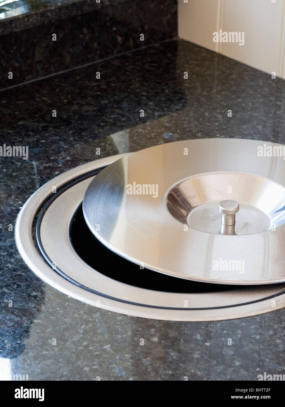 Closeup of kitchen worktop with chrome lid on fitted compost bin Stock