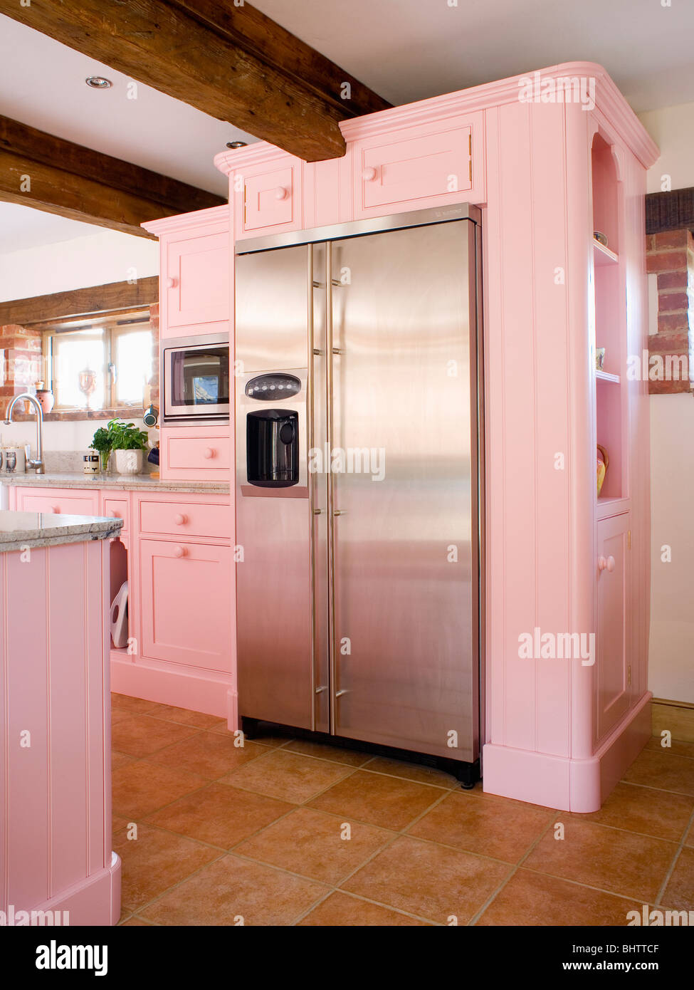 Large stainless steel American-style fridge-freezer in pastel pink fitted unit in country kitchen Stock Photo