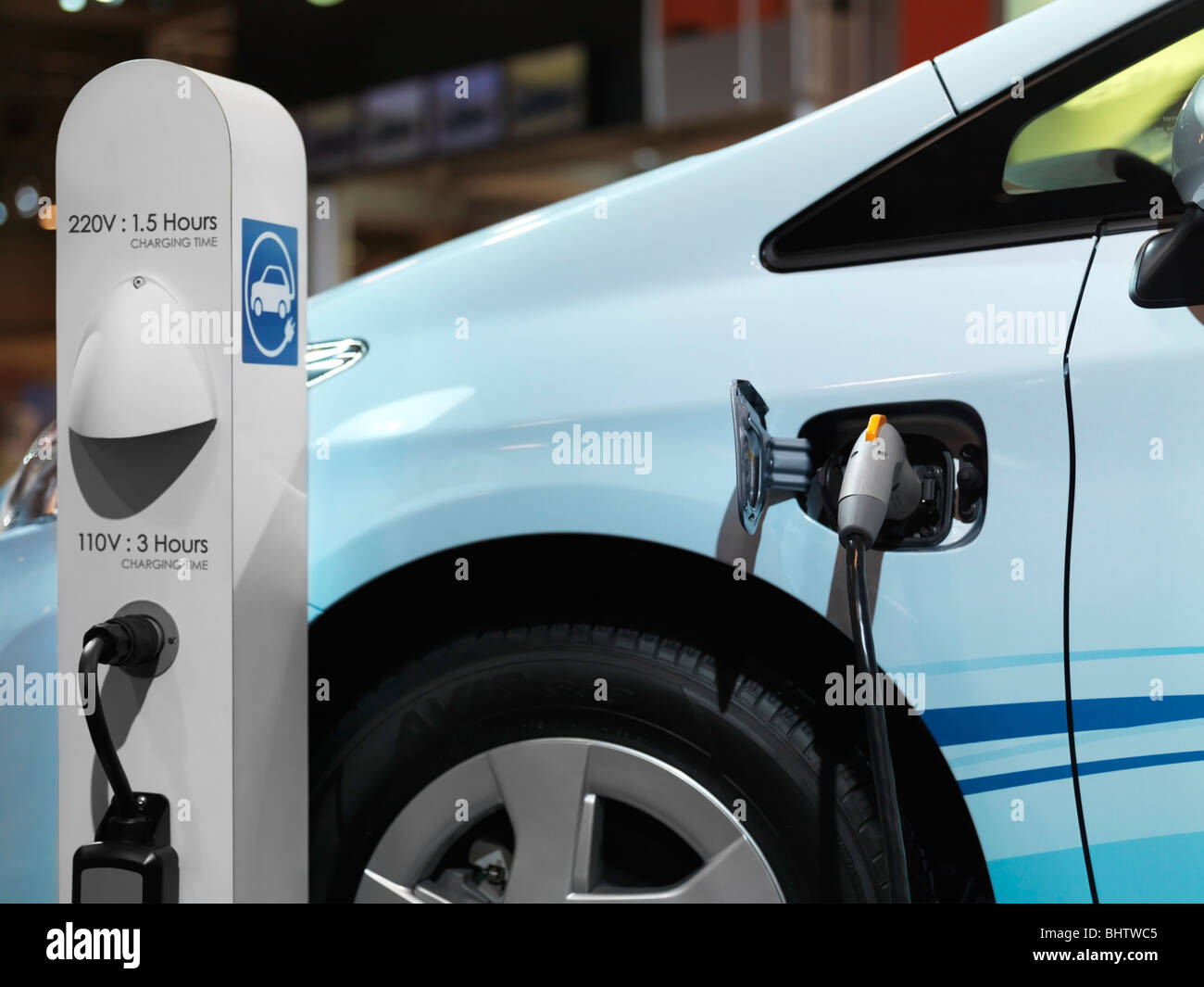 Electric car recharging batteries at a charging station Stock Photo