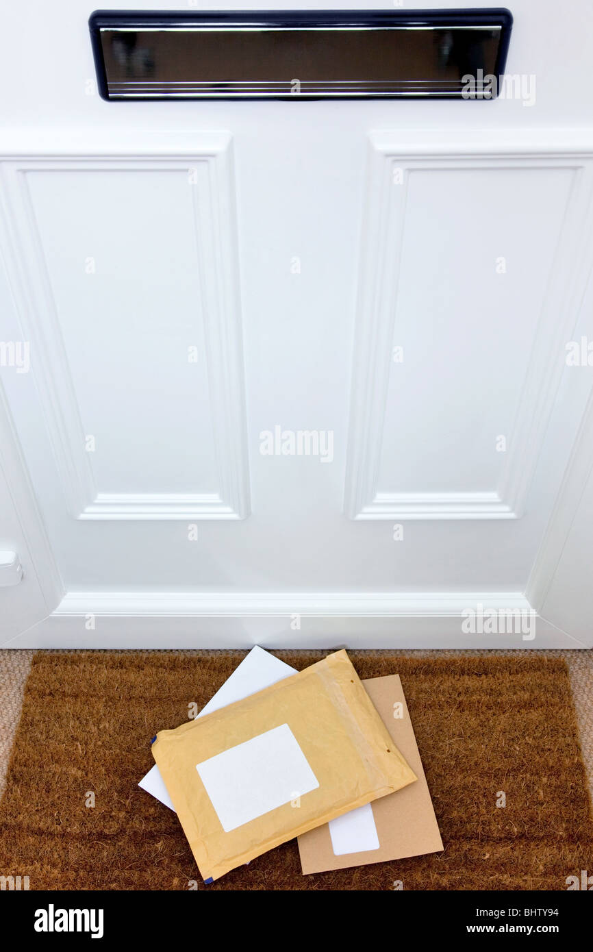Letters and a package lying on a doormat, blank labels to add your own name and address, focus on the letters. Stock Photo