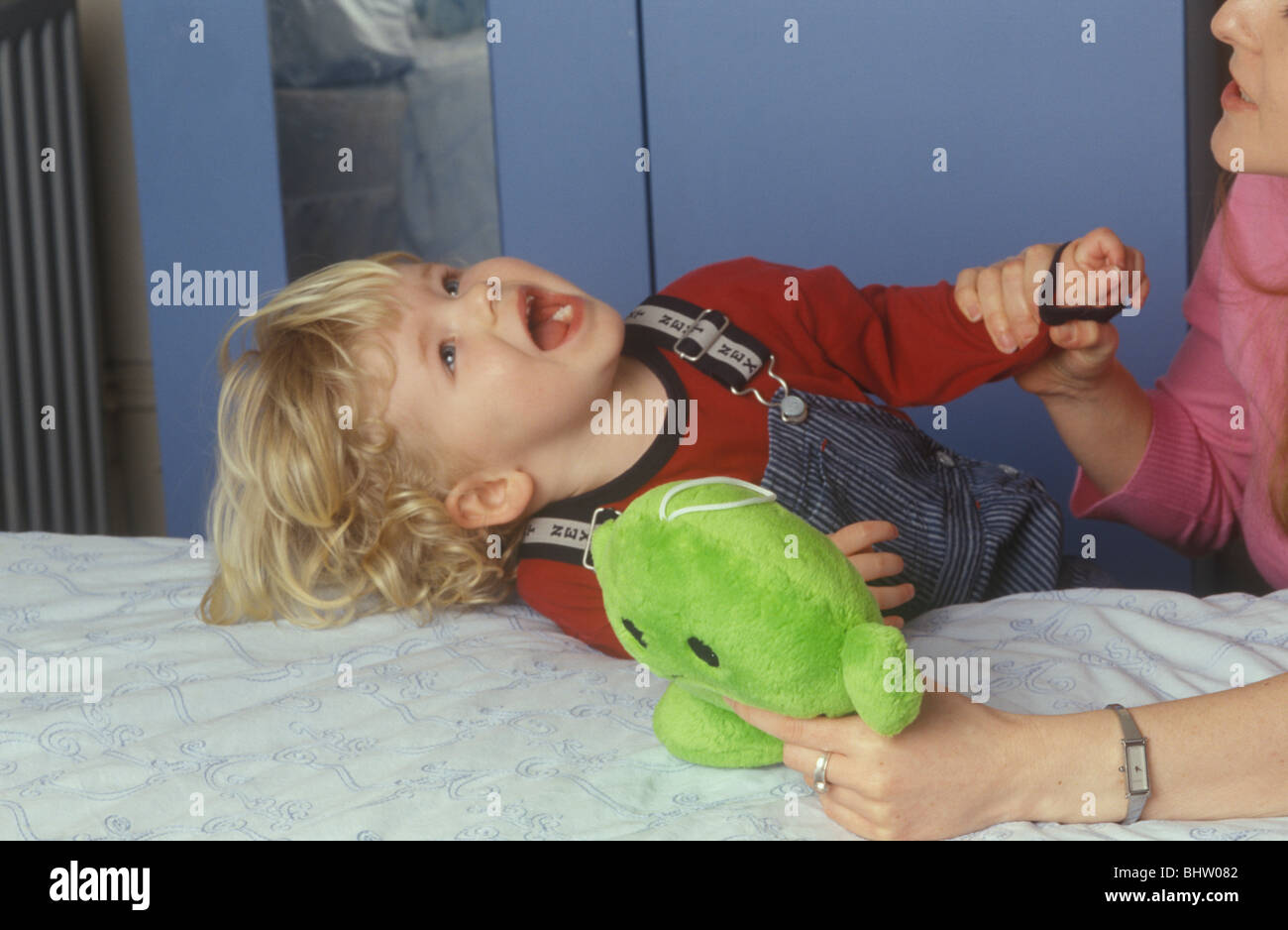 toddler having a tantrum as his mother tries to restrain him Stock