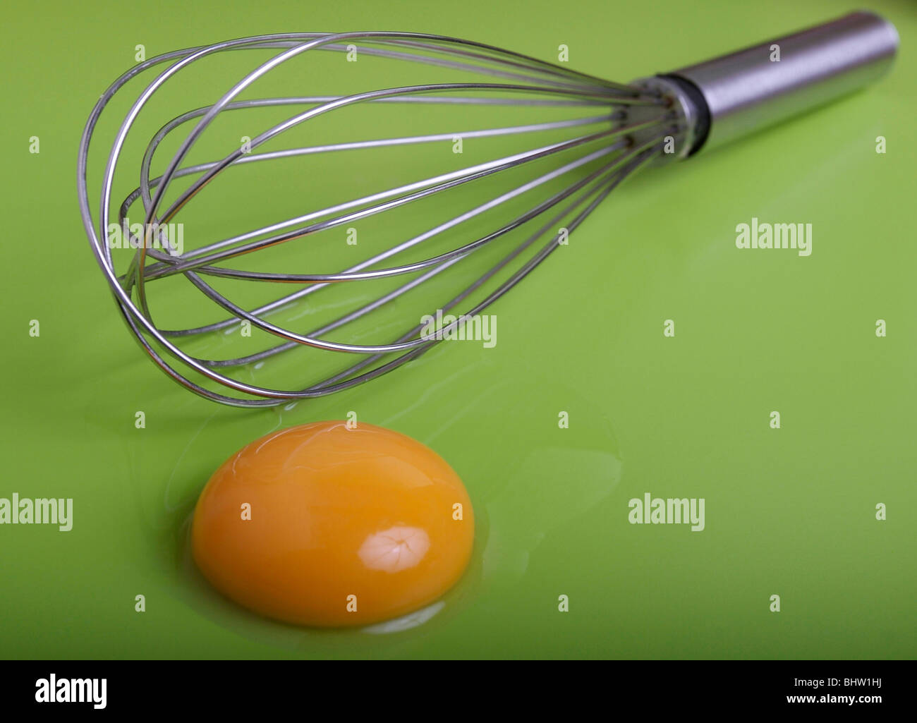 whisk with egg yolk on green background Stock Photo Alamy