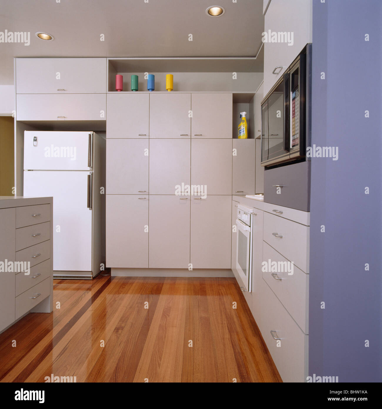 Wooden Flooring In Modern White Kitchen With Large Fridge Freezer And Wall To Ceiling Storage Cupboard Stock Photo Alamy